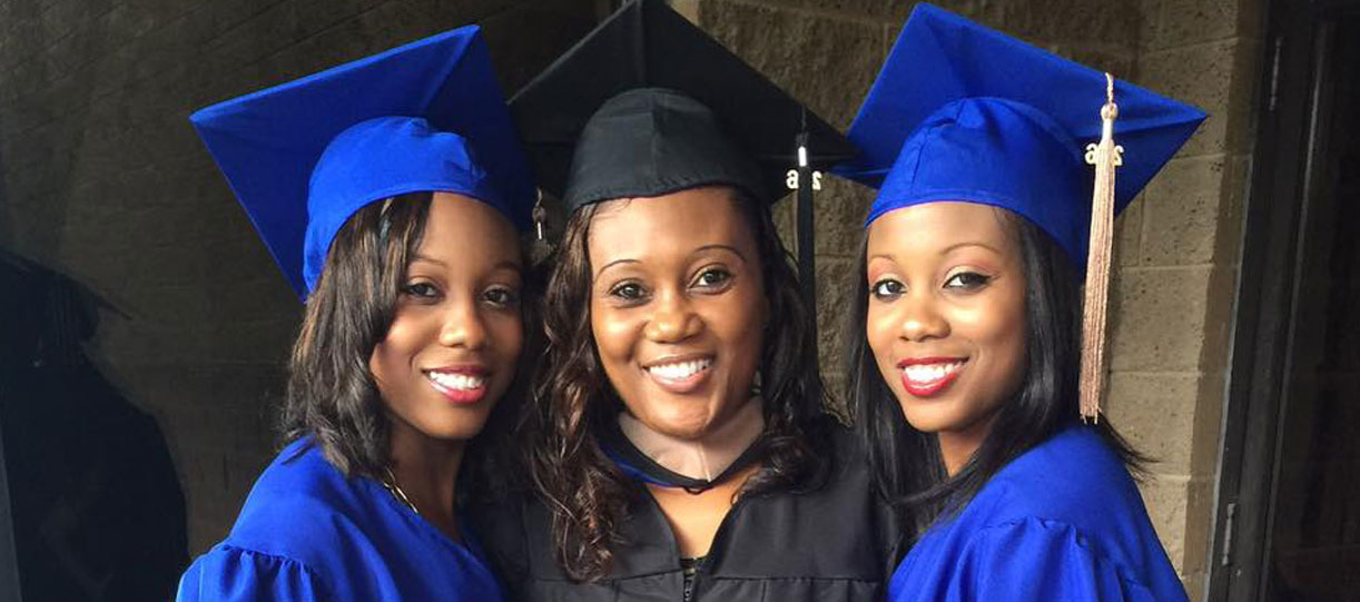 Graduate Adella Walker in cap in gown posing with her two daughters, also in cap and gown, at Spalding Commencement ceremony.