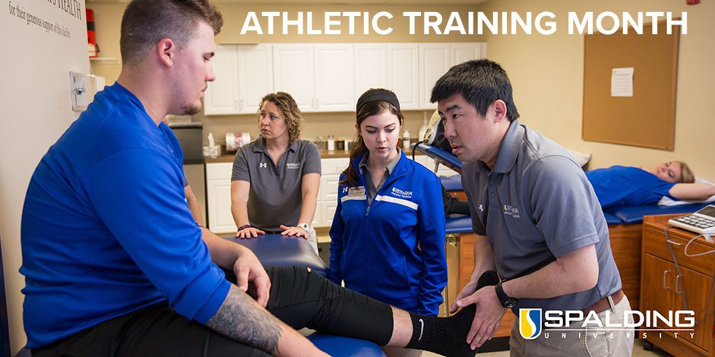Spalding athletic trainers work on a student's foot on a training table with an "Athletic Training Month" banner across the top.
