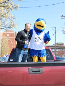 Student body President Chris Muncy and the Spalding blue and gold eagle mascot pose while standing outside in the bed of a pickup truck