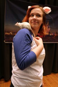 A white rat climbs of the shoulder of a caring female student, who is also wearing costume mouse ears
