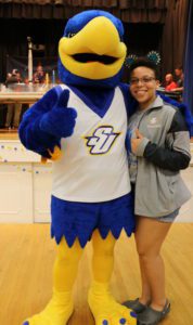 Spalding blue and gold eagle mascot hugs and poses with a Spalding female student. Both give thumbs up