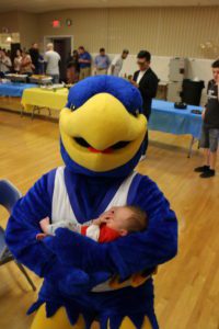 The big blue and gold Spalding eagle mascot holds a sleeping baby in its arms