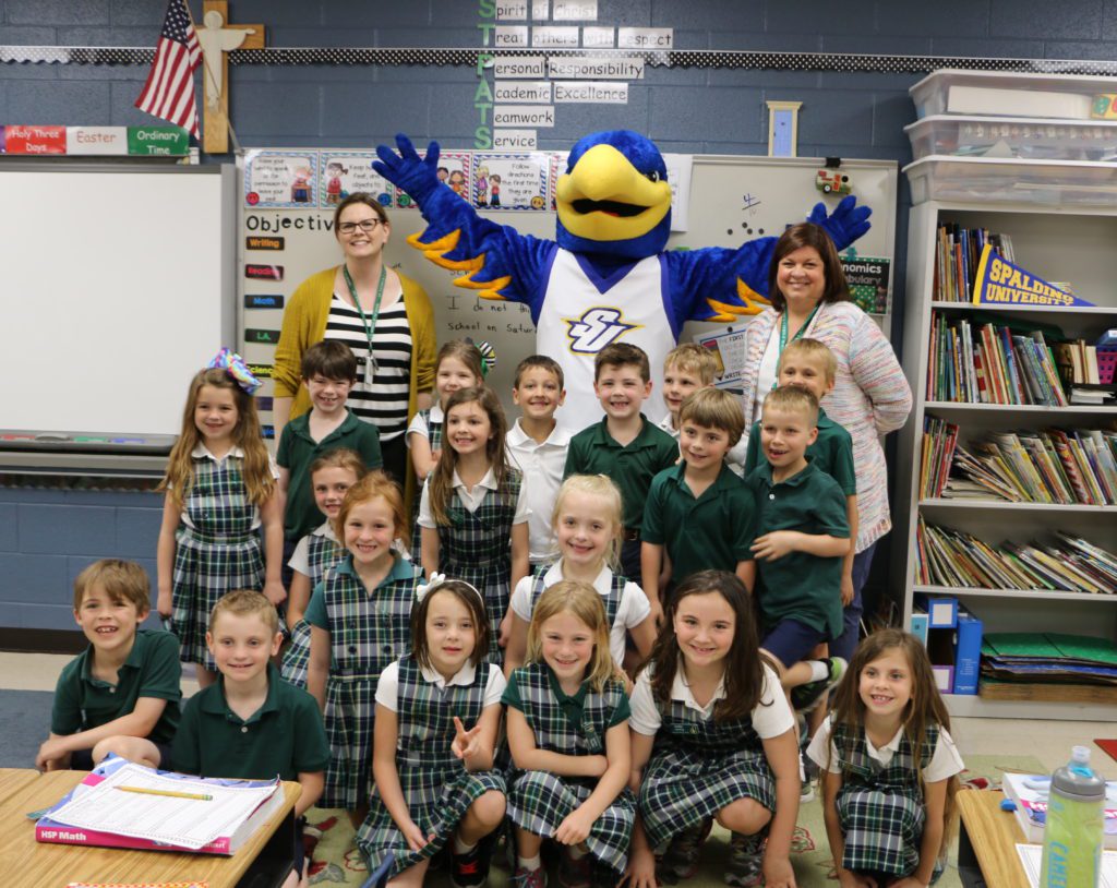 Smiling first-grade boys and girls wearing blue and green school uniforms pose with Spalding's big blue-and-golden eagle mascot