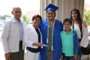Yamira Rafael, wearing cap and gown, surrounded by smiling relatives