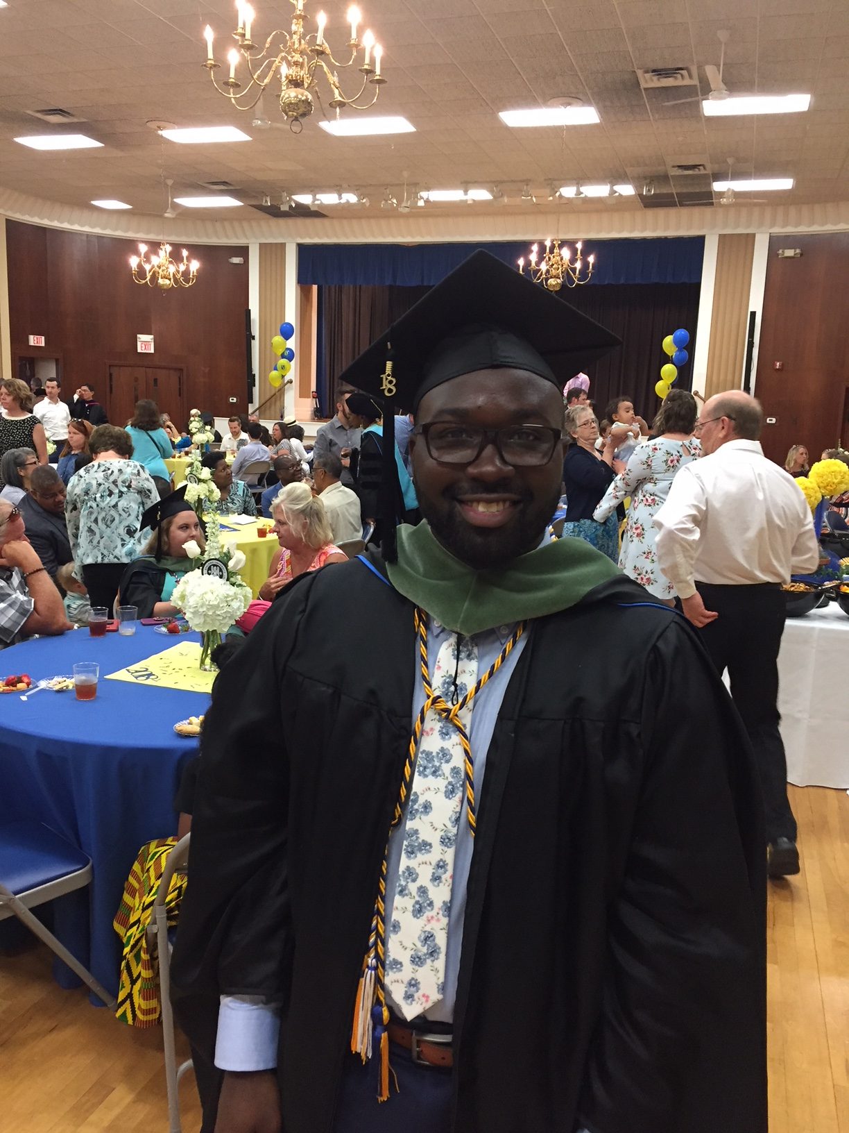Rico Thomas, wearing black cap and gown at commencement reception