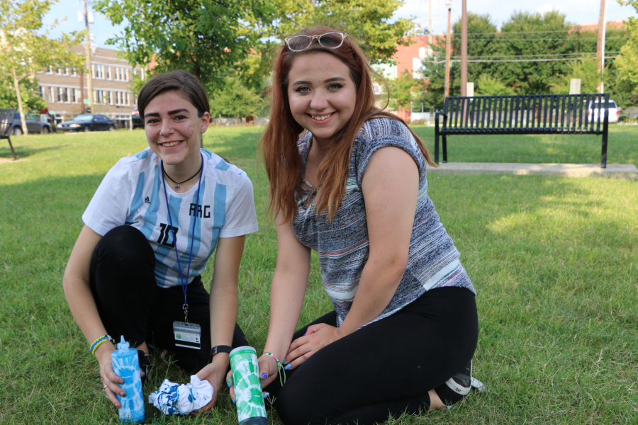 Female college students Emma Wade, left, and Kelly McCulloch smile while sitting on a campus lawn