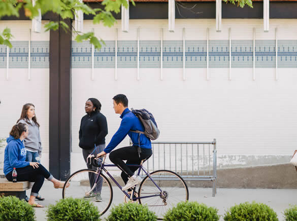 Student rides bike in front of library