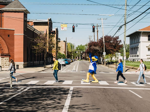 Students and eagle mascot walking across street crosswalk