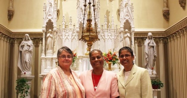 Sisters of Charity of Nazareth Adeline Fehribach, Sangeeta Ayithamattam and Jackulin Jesu pose inside a Catholic church sanctuary