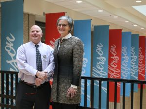 Ty Handy and Tori McClure pose for a photo in front of a row of JCTC banners