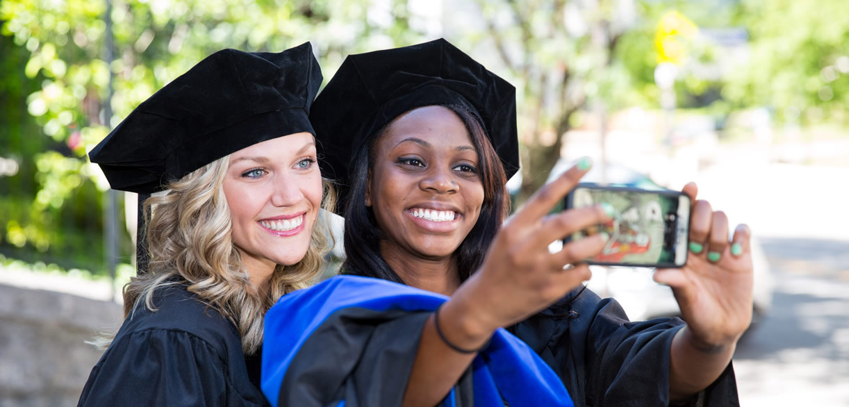 PsyD students in regalia take selfie at graduation
