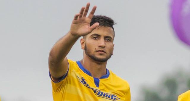 Spalding soccer player Kasim Alsalam, waving to crowd, wearing gold jersey and blue shorts
