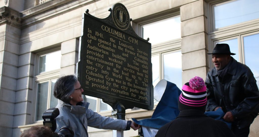 Tori McClure and Rahman Ali pull a cloth cover off of a bronze Columbia Gym historical marker