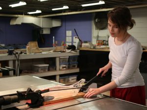 A Spalding Creative Arts student cuts a piece of wood on a table saw