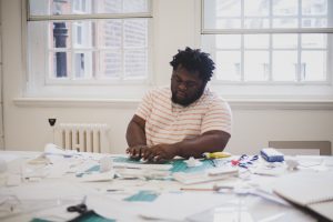 Victor Edwards working with paper on cutting board