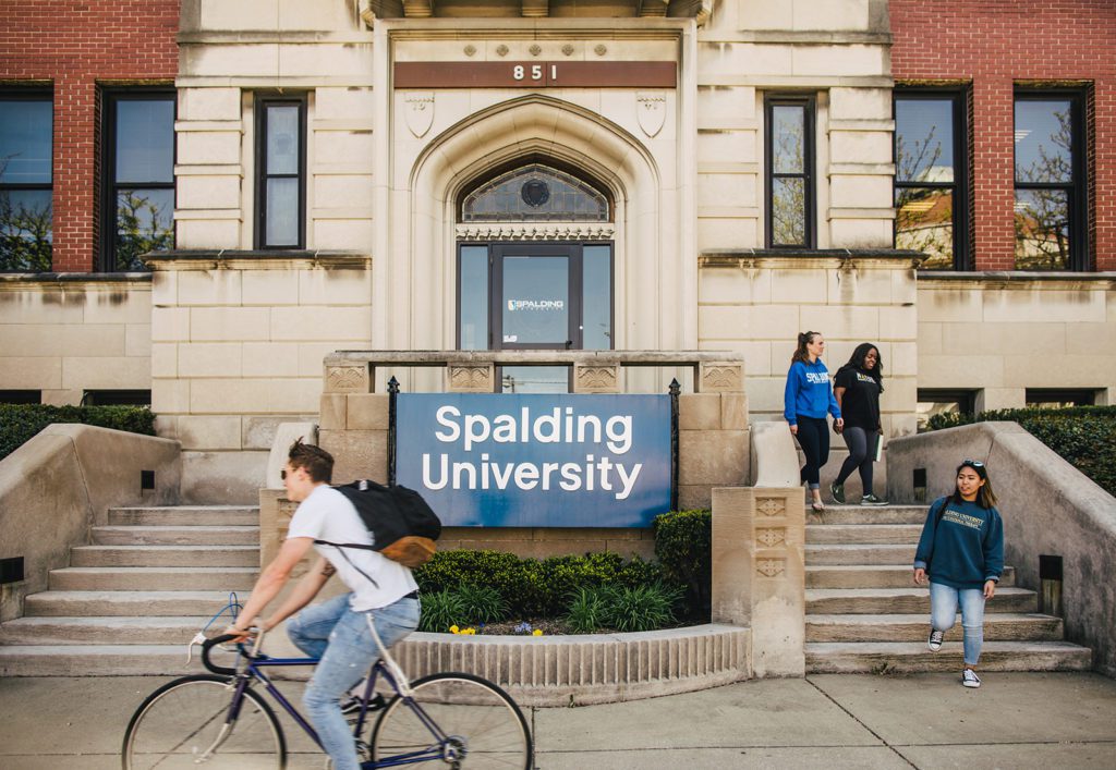 Student rides bike past Spalding Mansion complex entrance