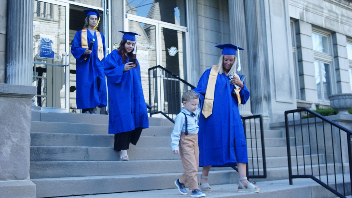 Spalding grad walking with her kid down steps outside Columbia Gym