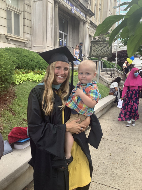 Spalding grad holding her kid outside after ceremony