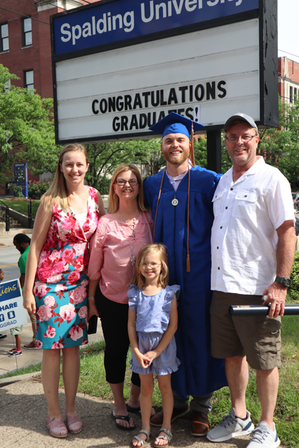 Spalding grad with family in front of congrat grads sign