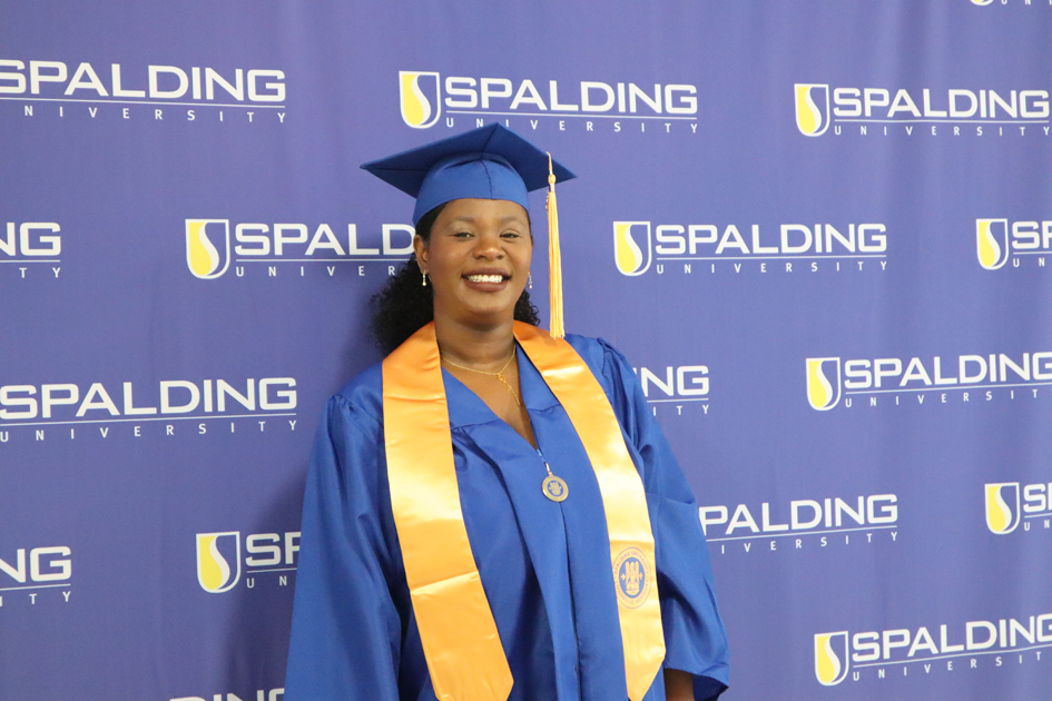 Spalding grad in front of Spalding University backdrop