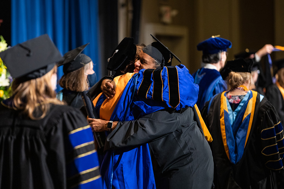 Spalding grad and professor hugging during ceremony