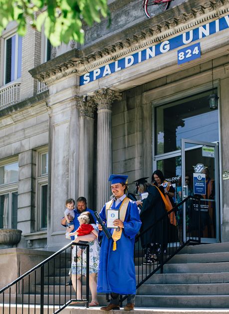 Spalding grad outside Columbia Gym on stairs