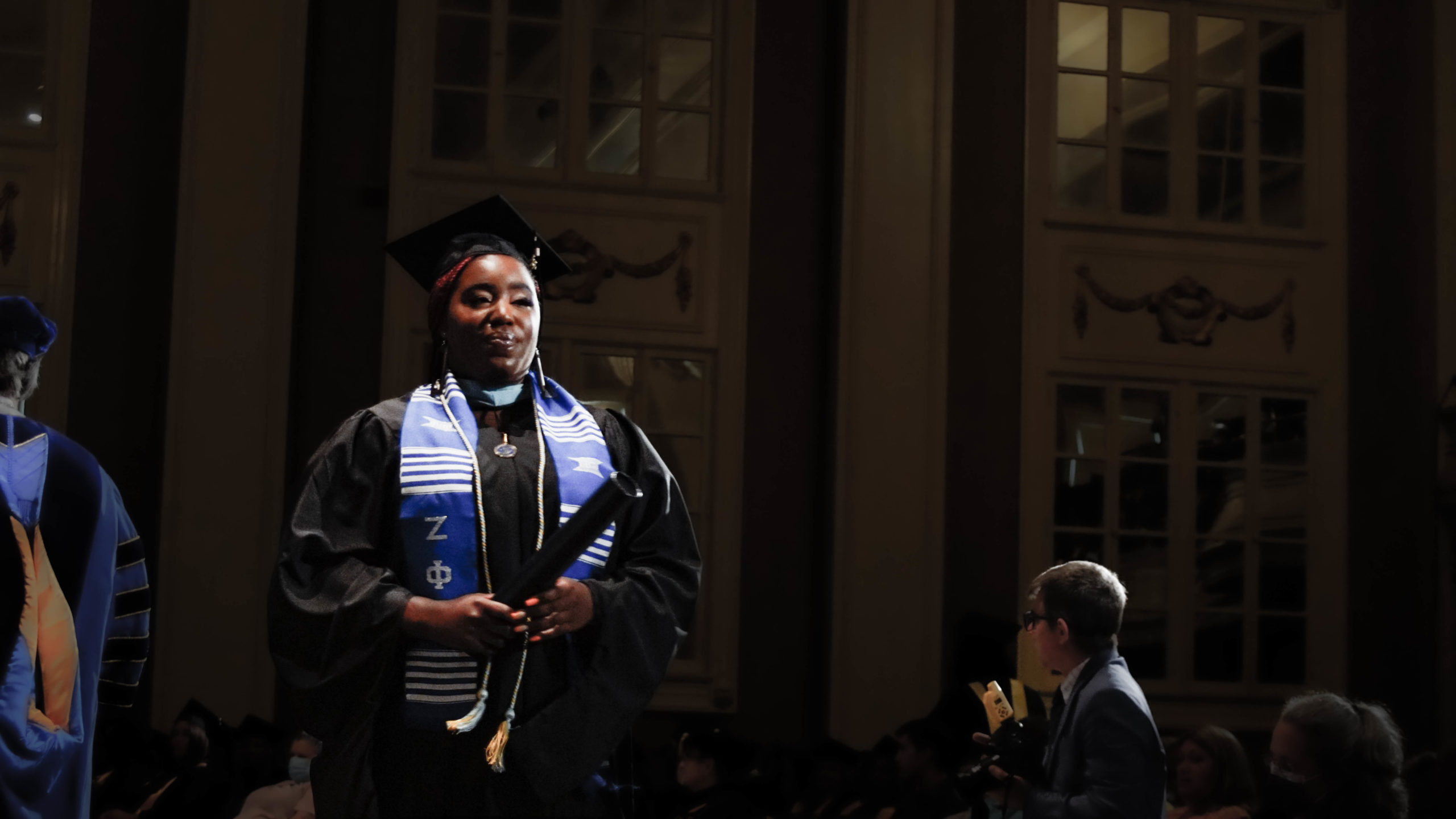 Spalding education grad with blue and white sash holding degree