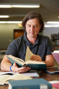 Spalding MFA Writing student in library looking through book