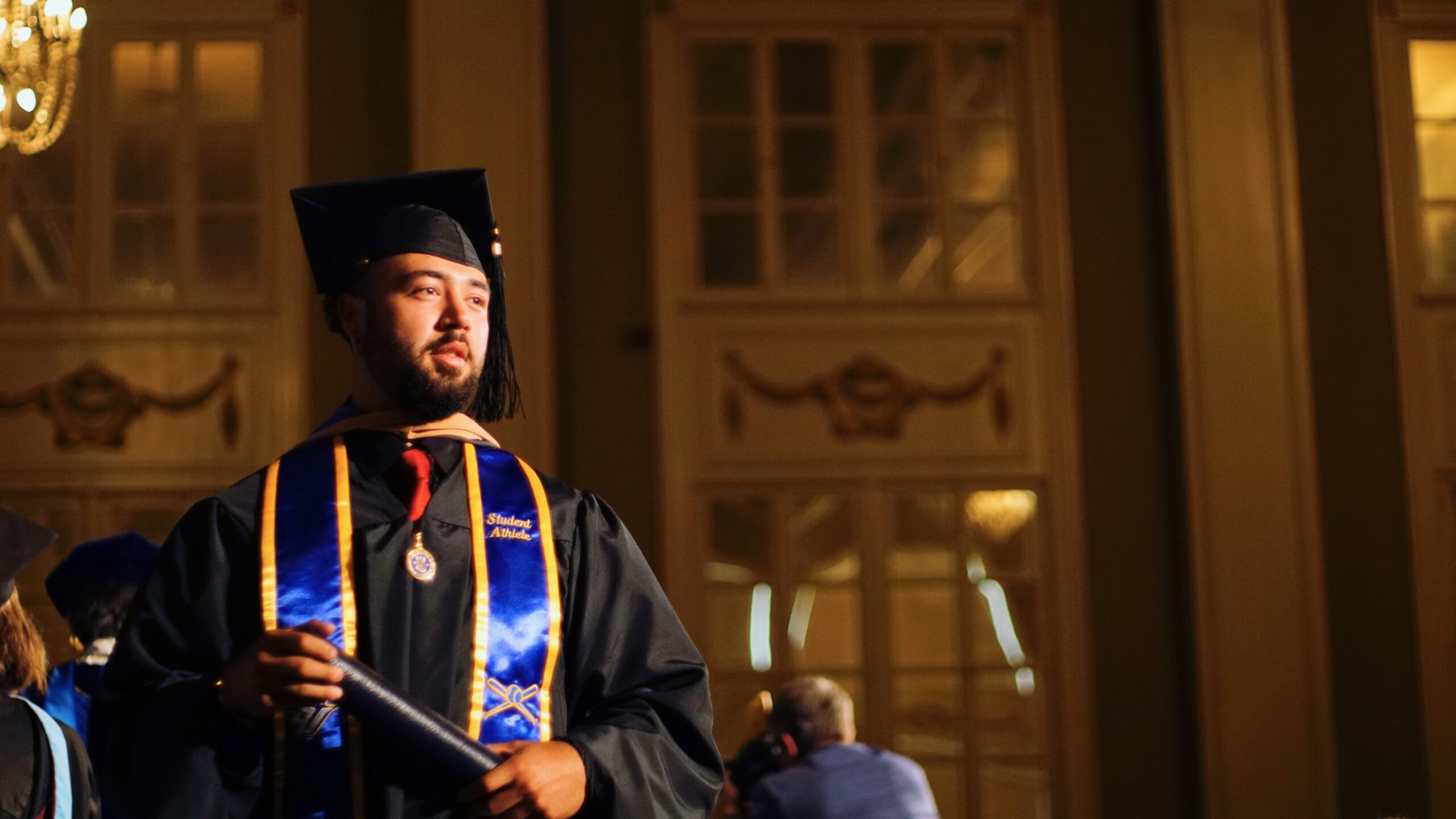 Spalding master's graduate in cap and gown with degree tube