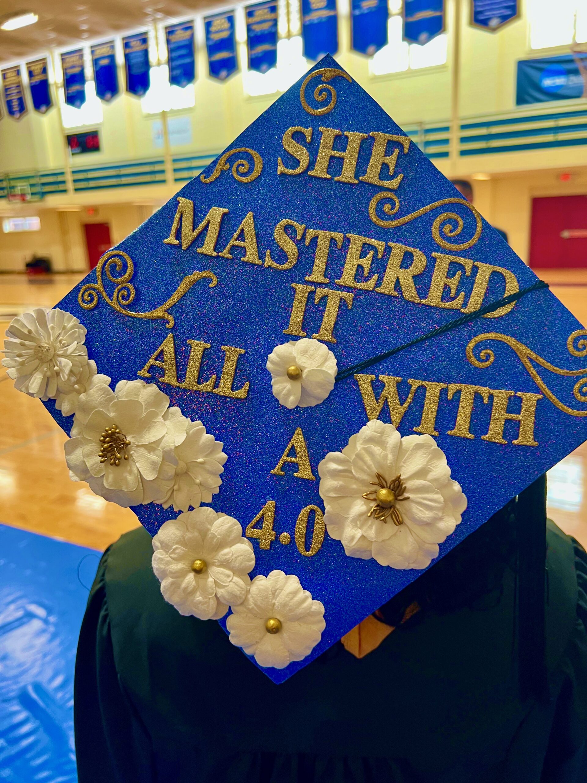 Decorated mortarboard reading "She mastered it all with a 4.0"