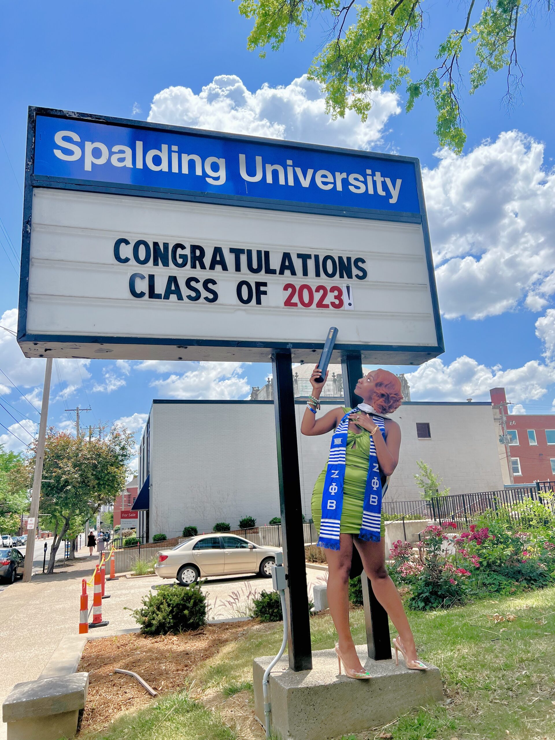 Spalding graduate posing with sign reading "Congratulations Calss of 2023"