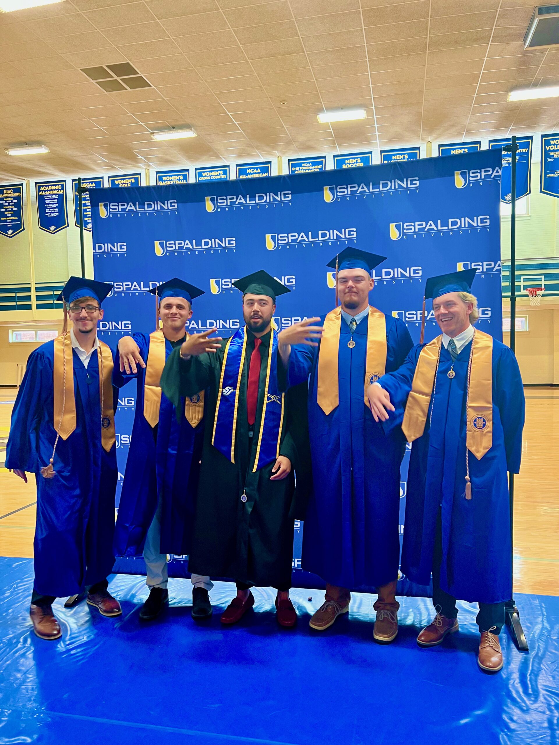 Group of Spalding graduates posing in front of Spalding backdrop