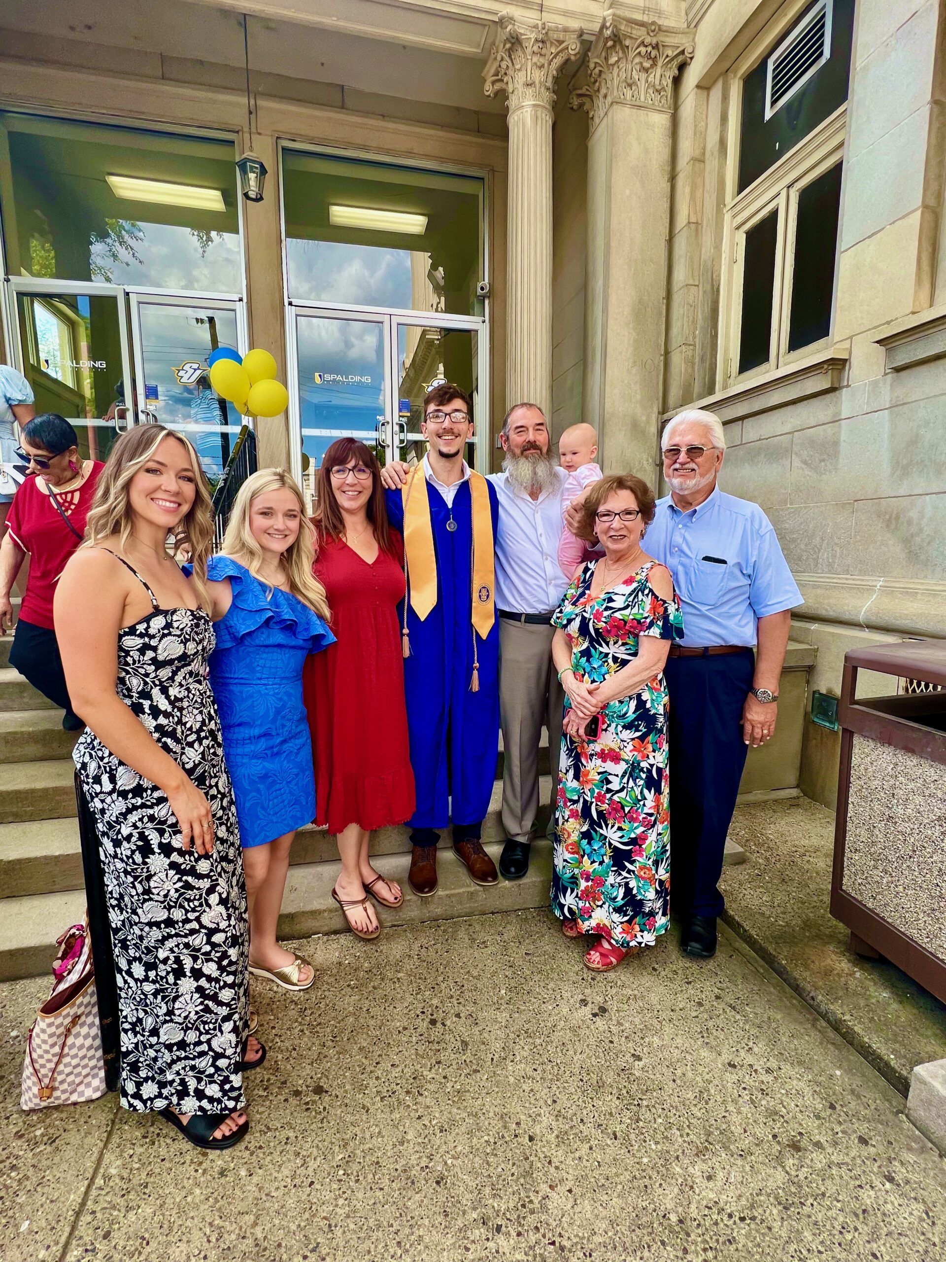 Spalding bachelor's graduate posing with family outside Columbia Gym
