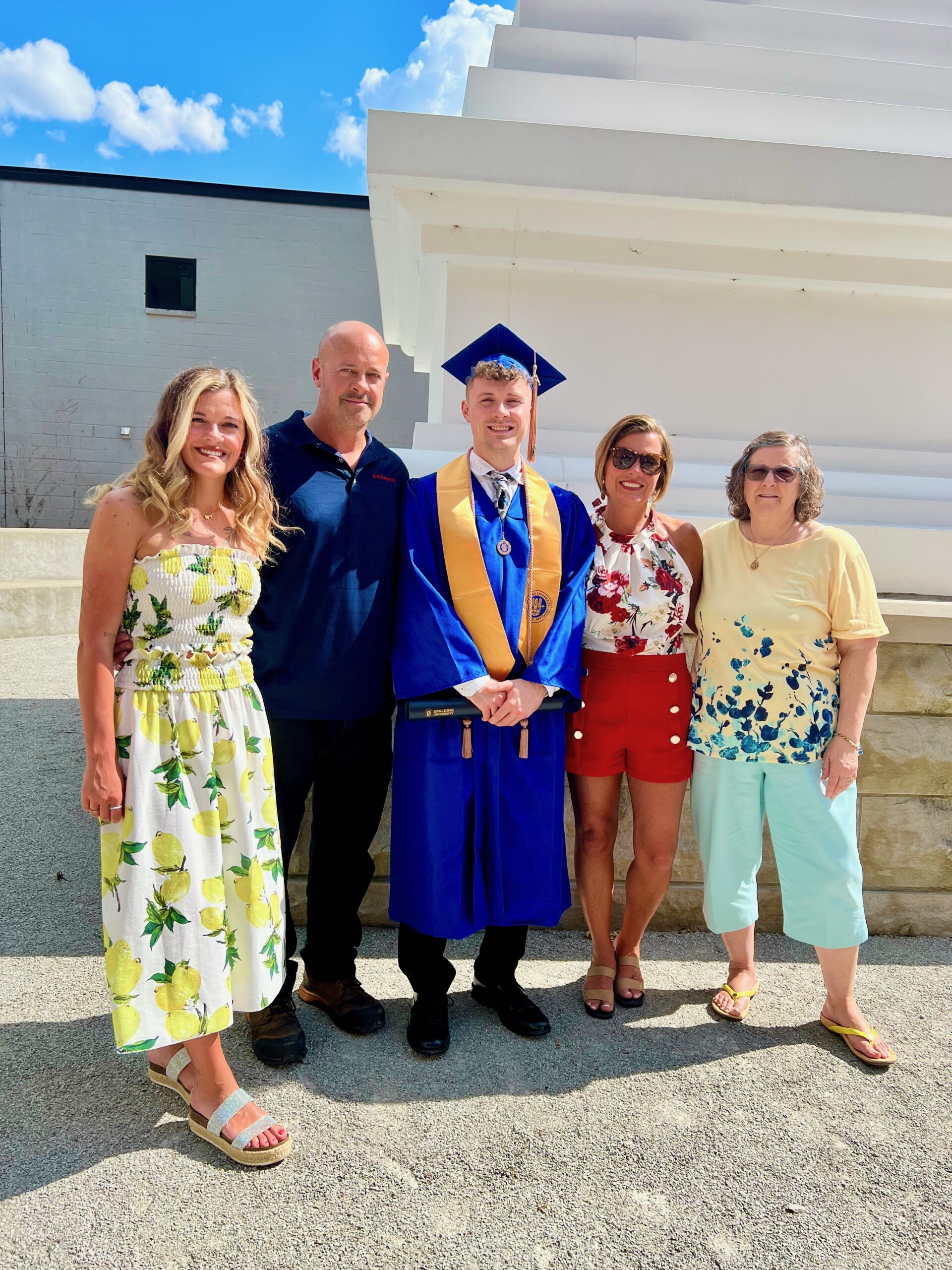 Spalding bachelor's graduate posing with family outside