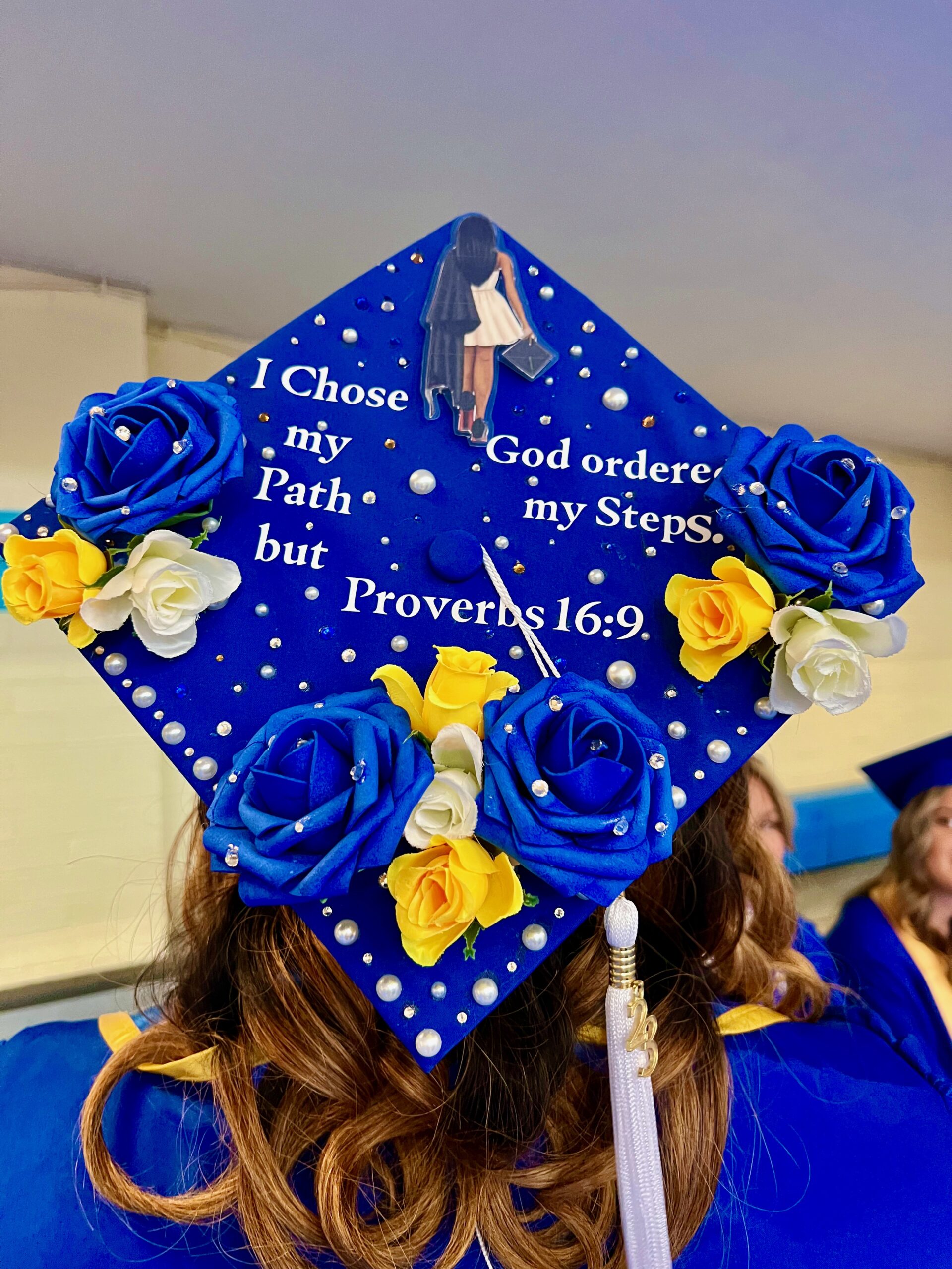 Decorated mortarboard reading "I chose my path but God ordered my steps. Proverbs 16:9"