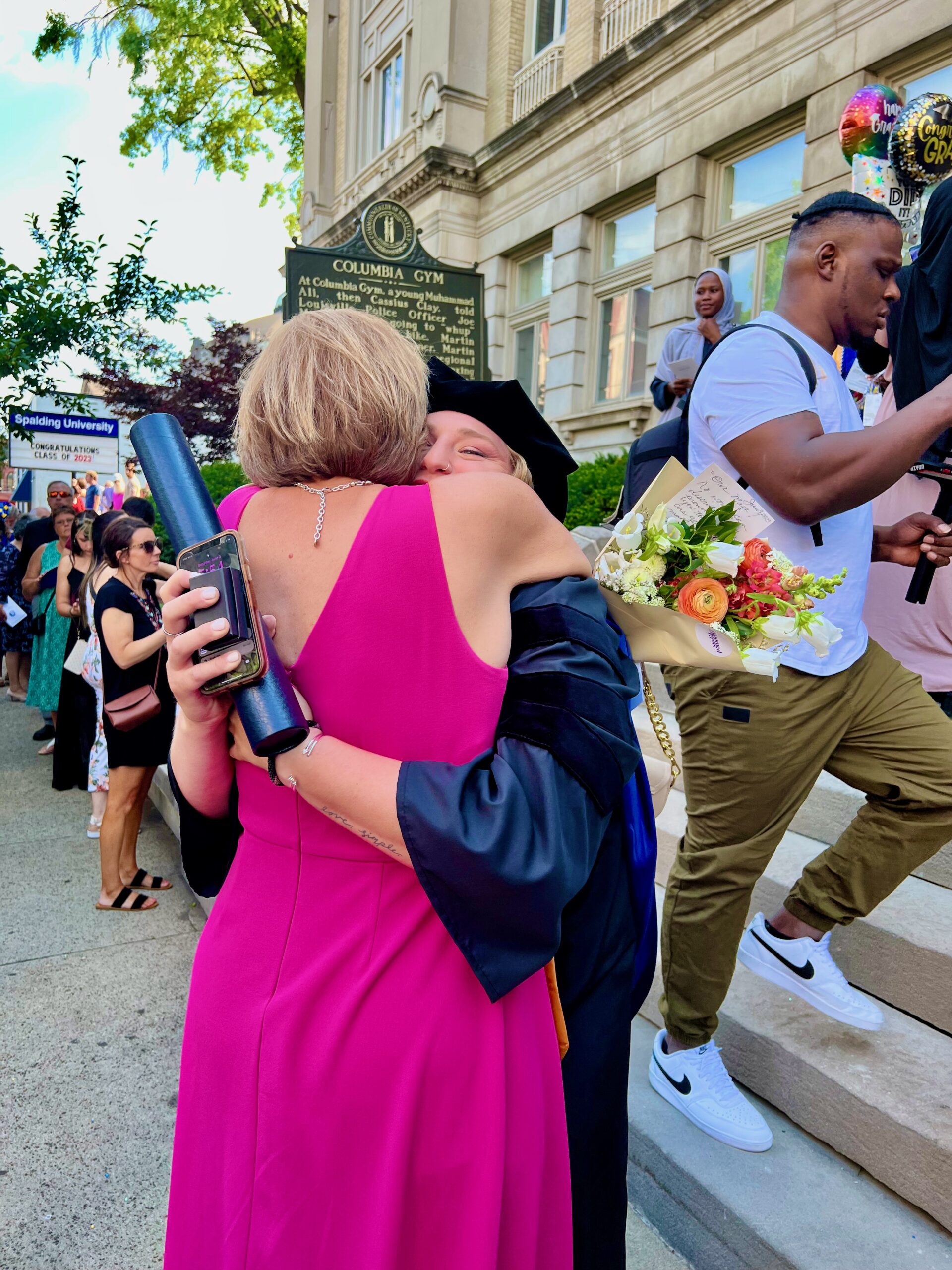 Spalding doctoral graduate hugging family member outside after ceremony