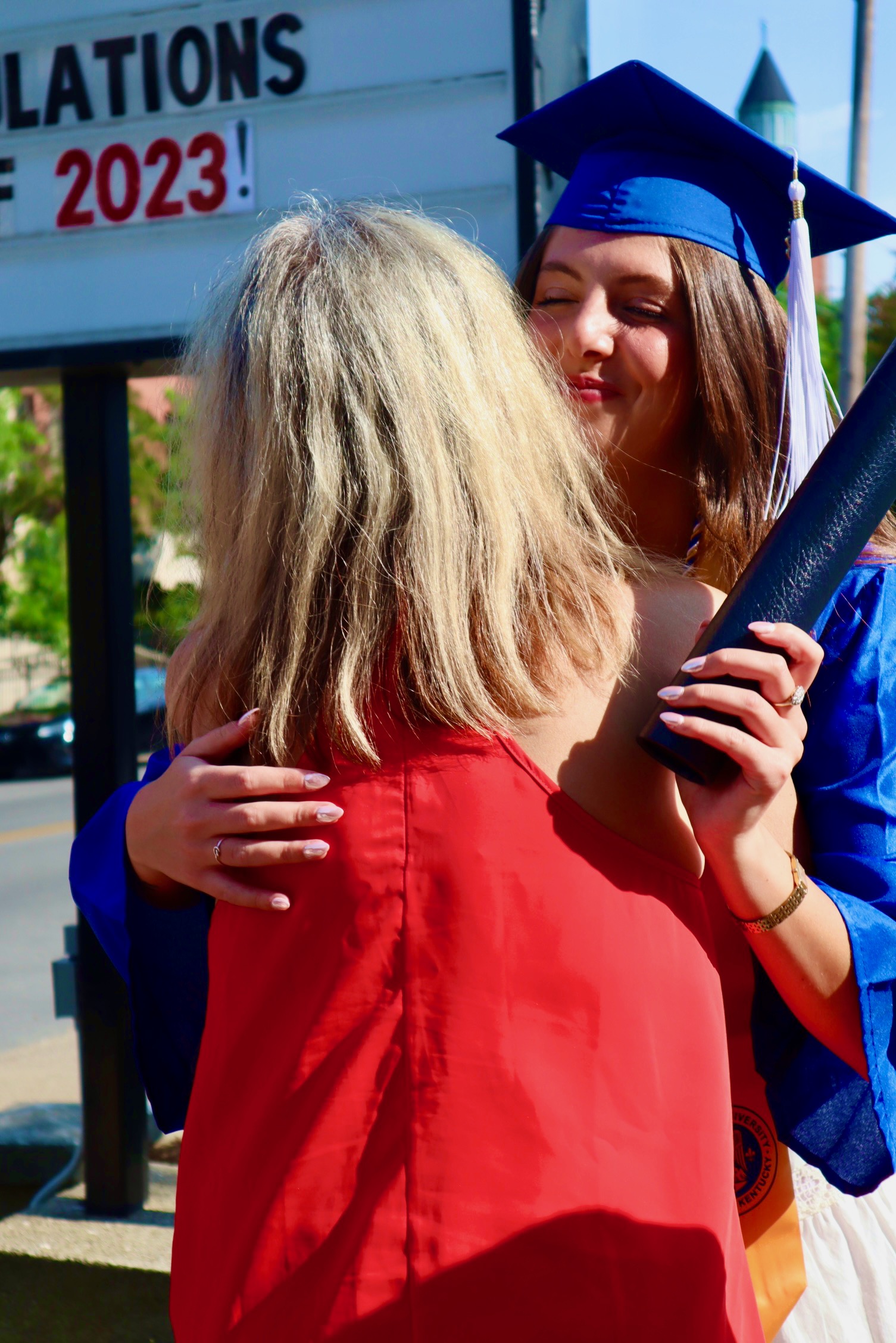 Spalding bachelor's graduate holding degree tube hugging mom