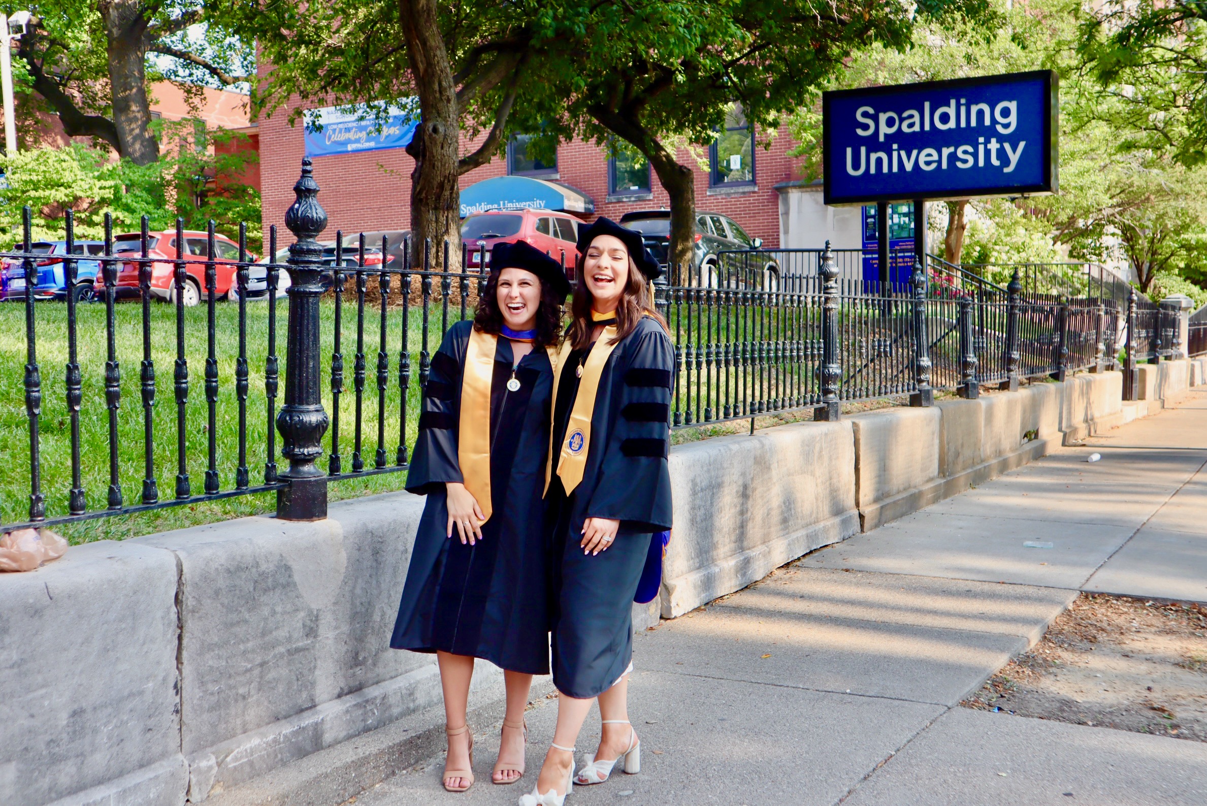 Two Spalding doctoral graduates posing for photo on the sidewalk