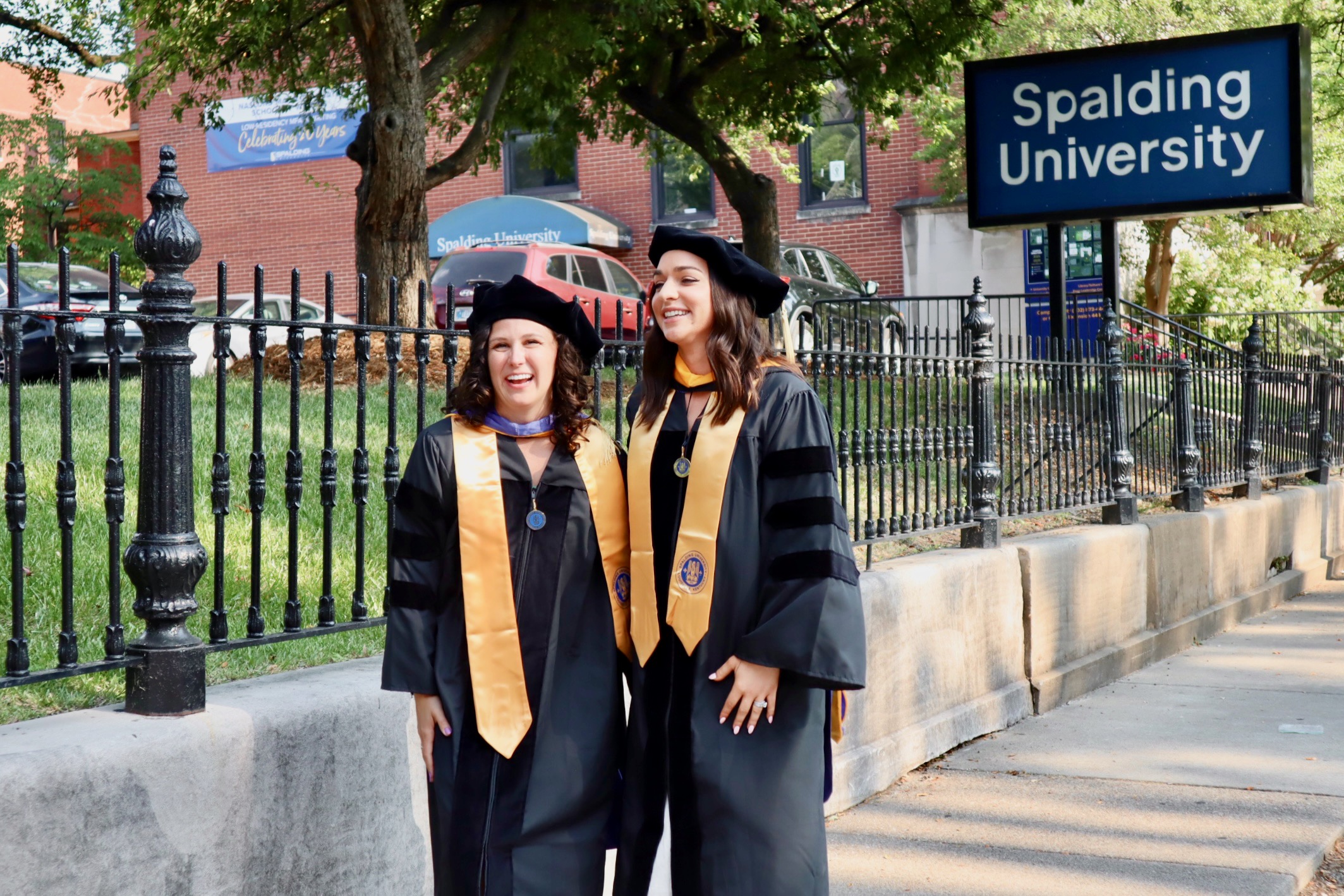Two Spalding doctoral graduates posing for photo on the sidewalk