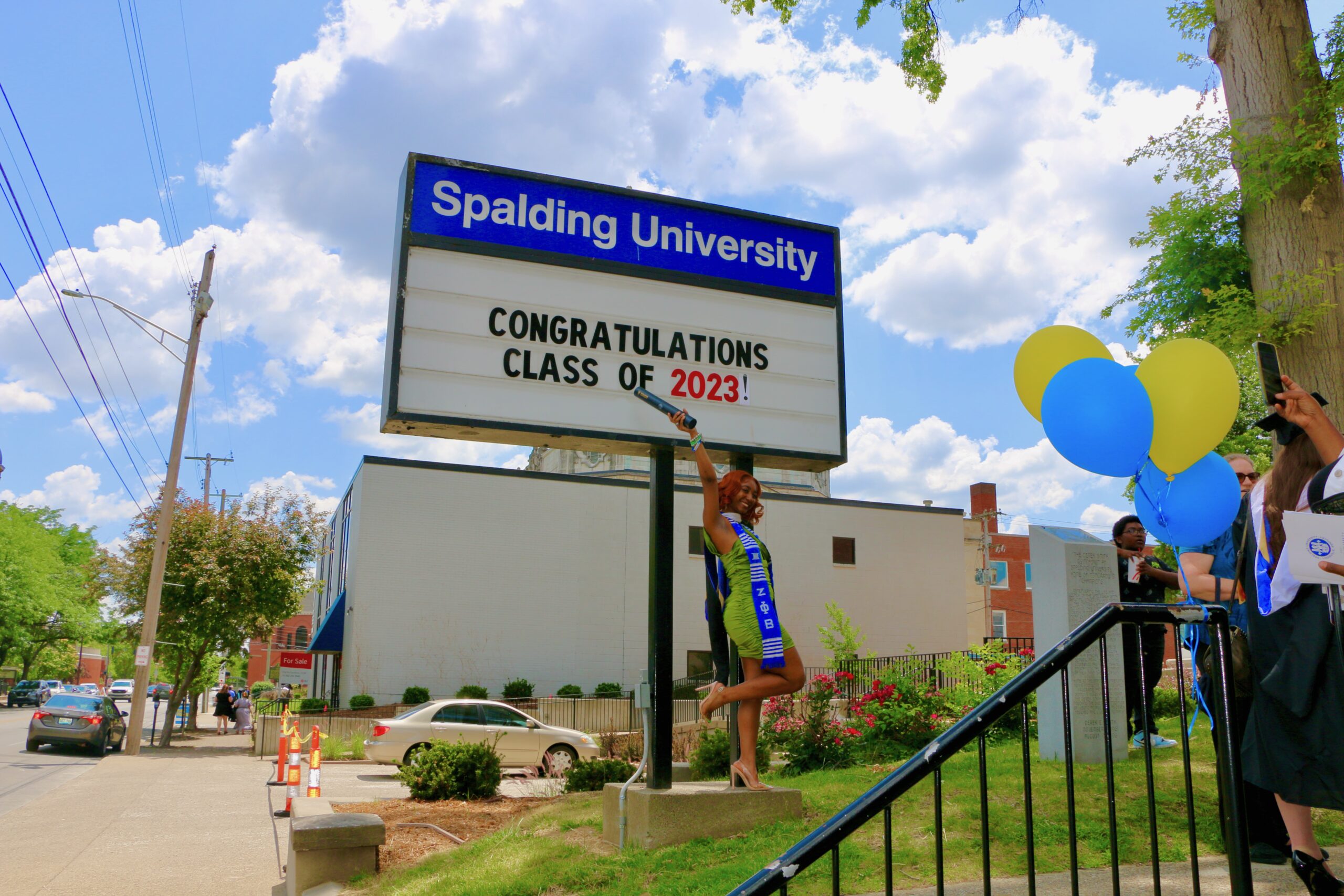 Spalding graduate posing with sign reading "Congratulations Calss of 2023"