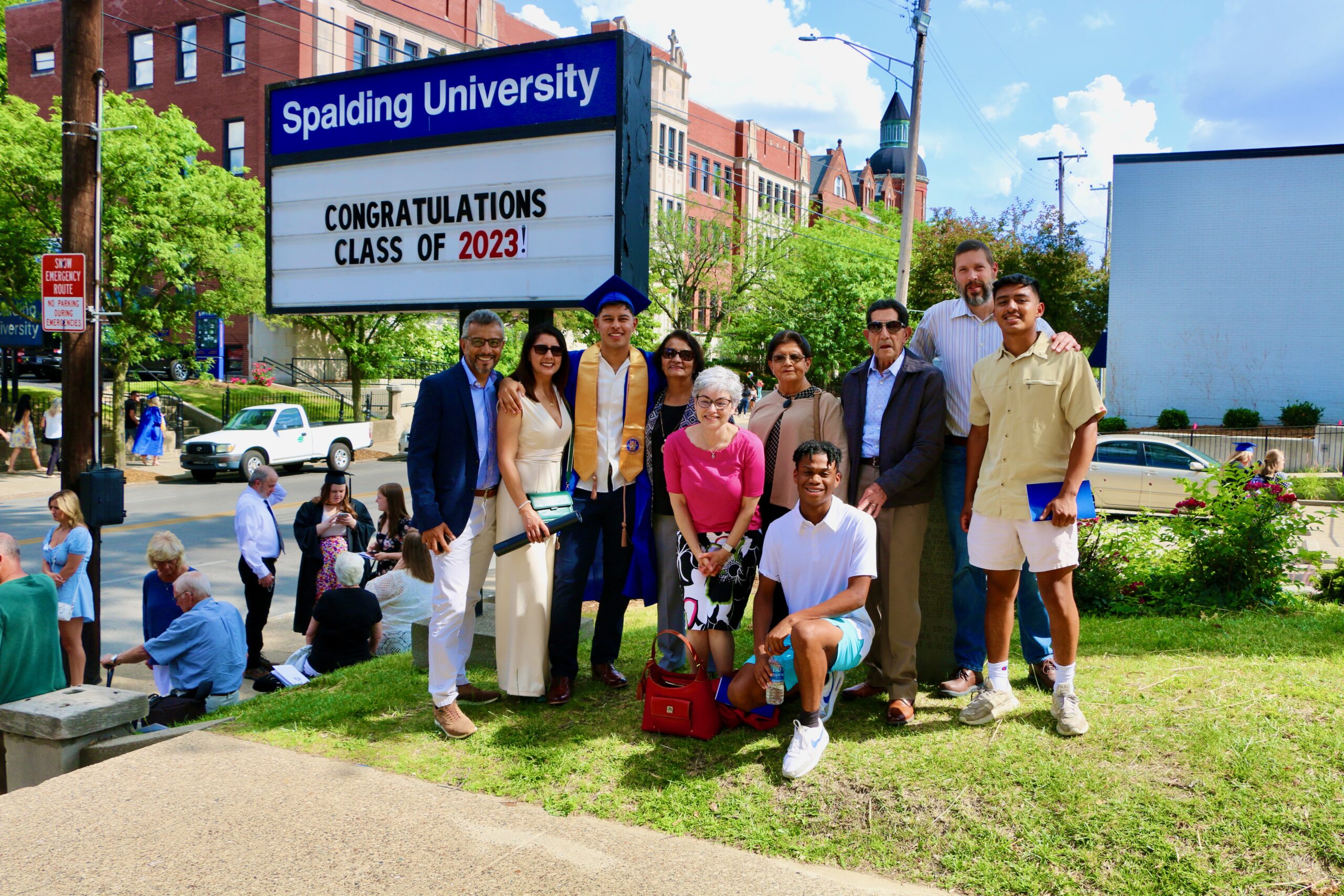 Spalding bachelor's graduate posing with family in front of sign reading "Congratulations Class of 2023"