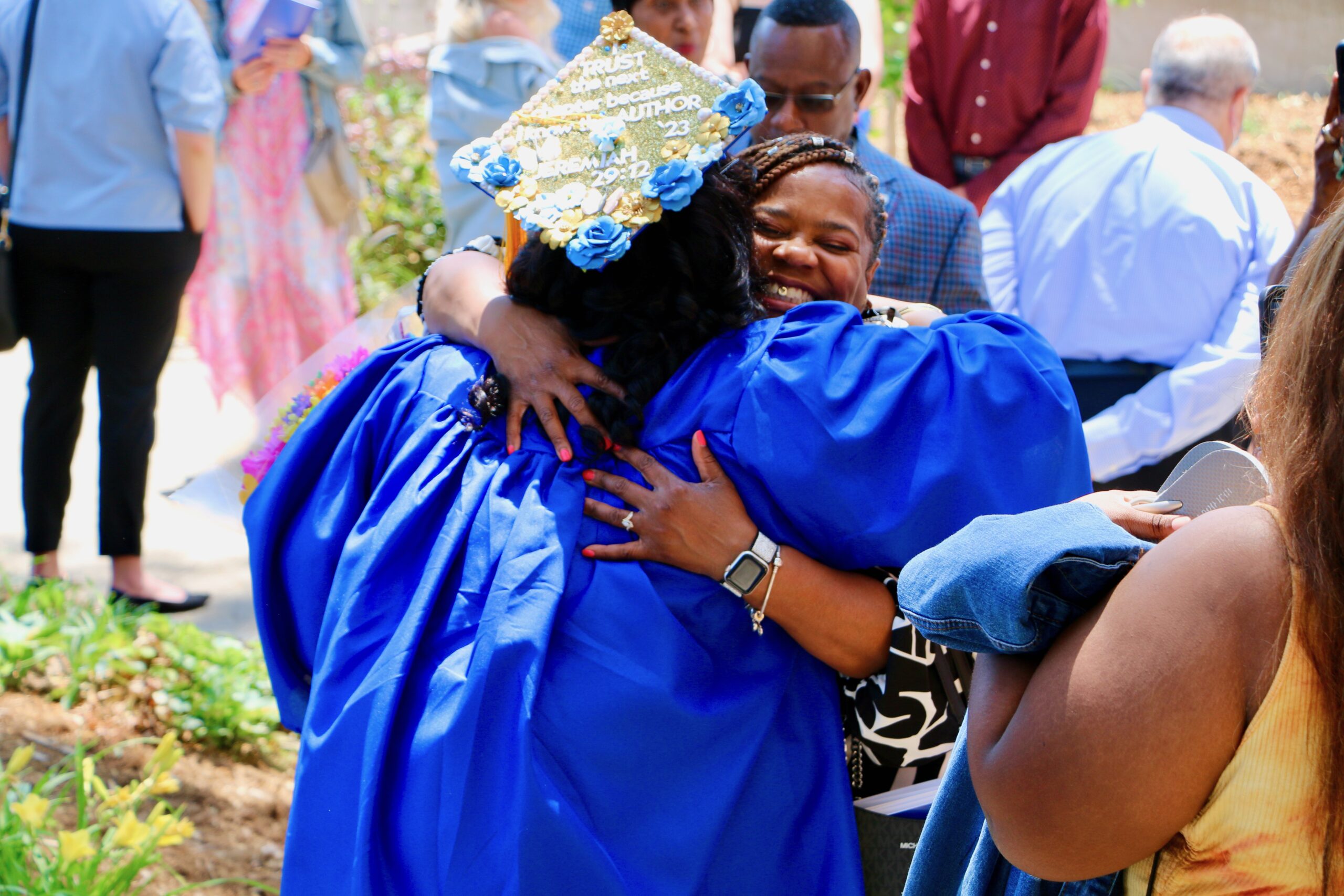 Spalding bachelor's graduate facing away from camera hugging family member