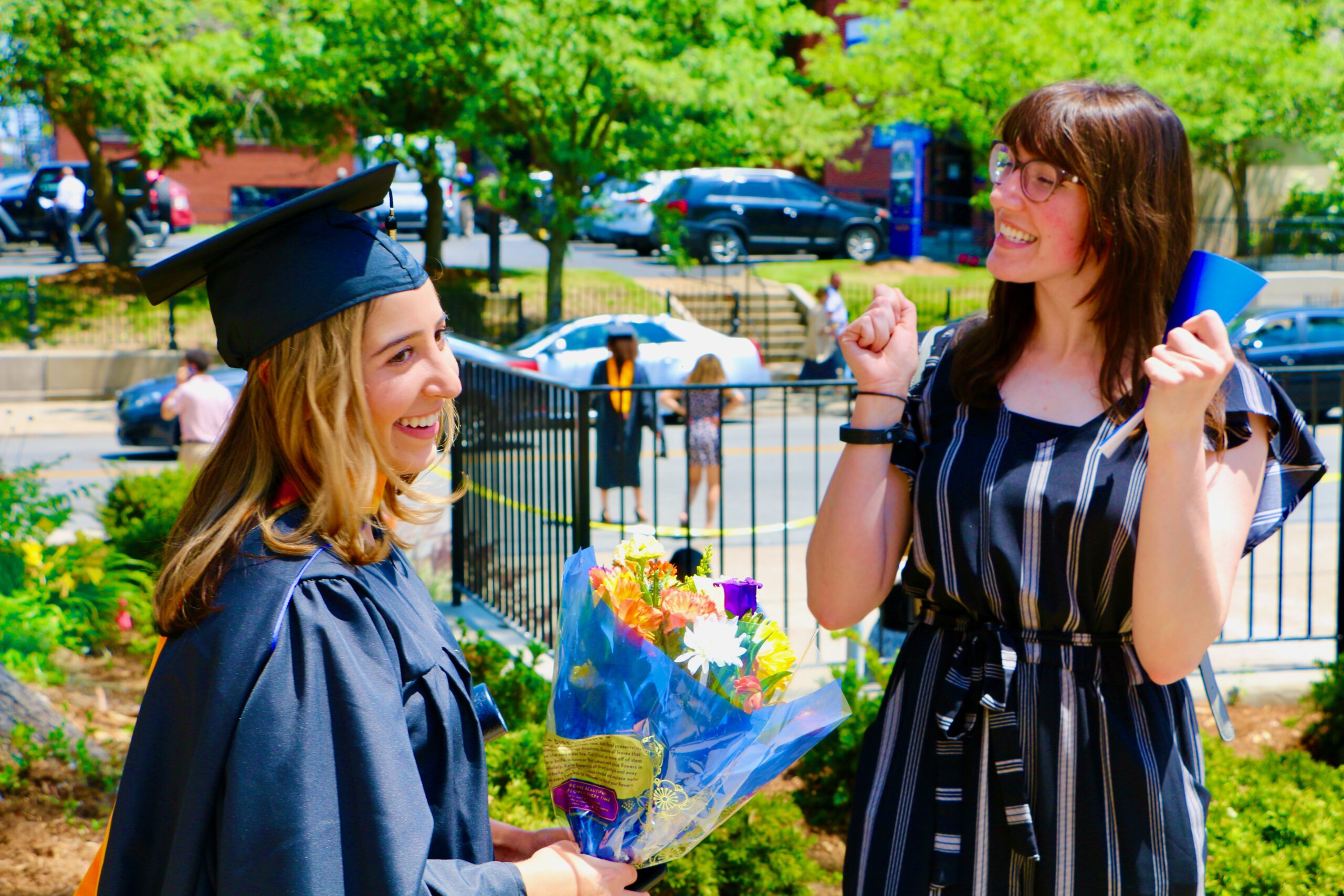Spalding master's graduate holding flowers talking with friend