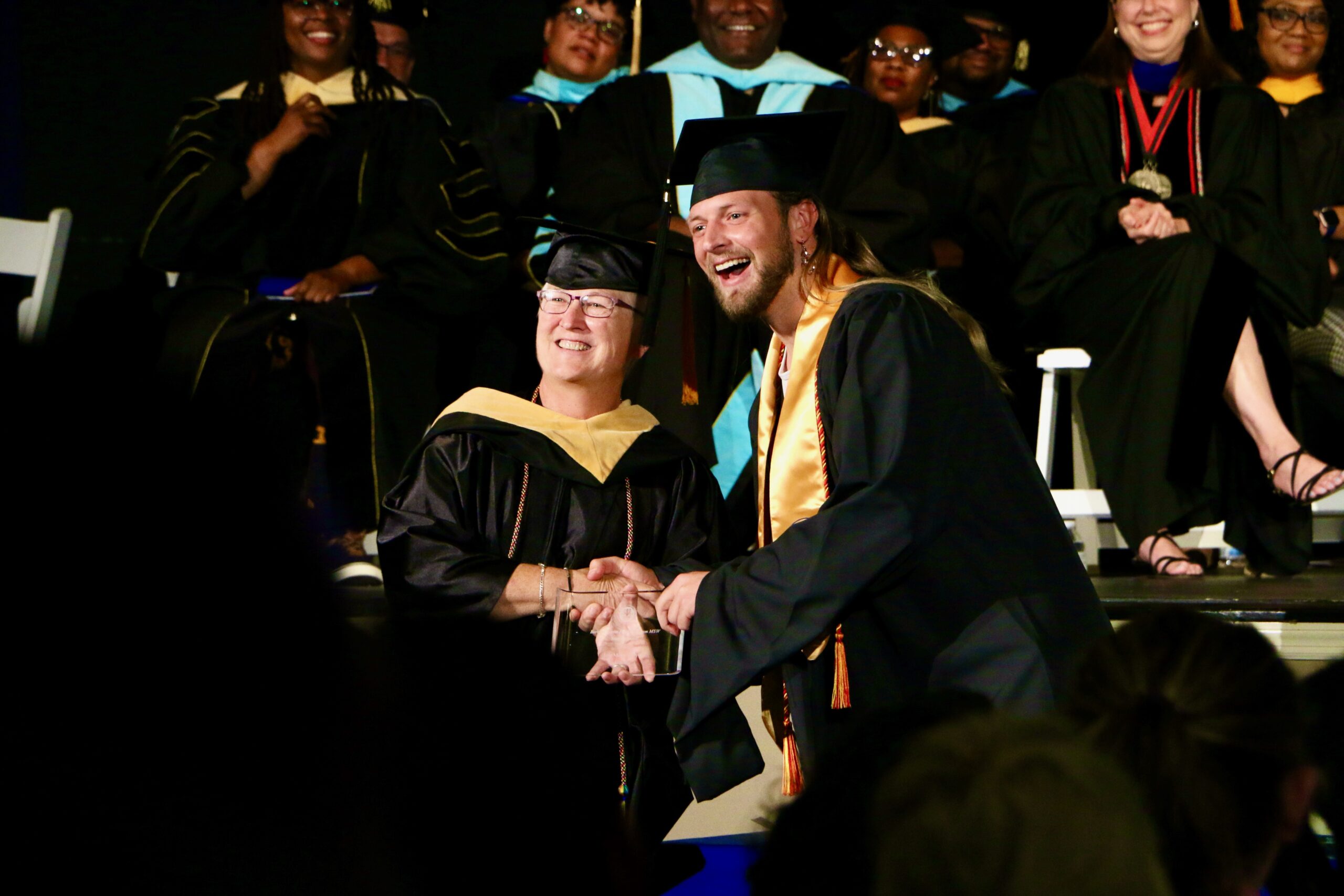 Spalding master's graduate shaking hands and receiving award from faculty