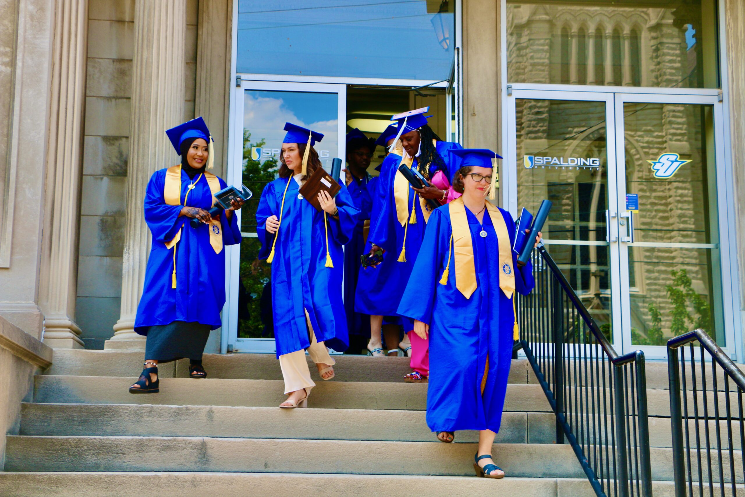 Spalding bachelor's graduates walking down steps outside Columbia Gym after ceremony