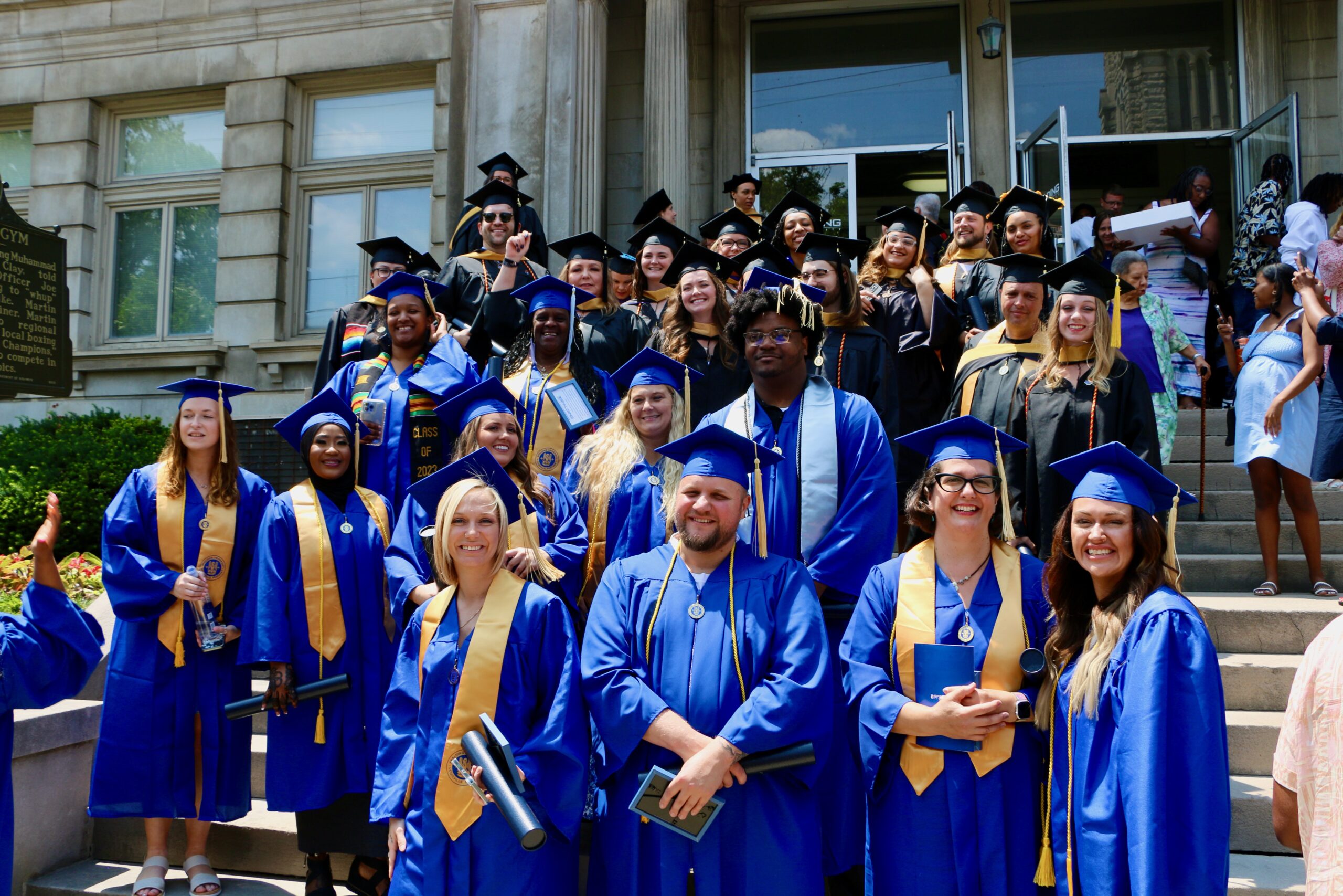Group of Spalding graduates outside on the steps of Columbia Gym