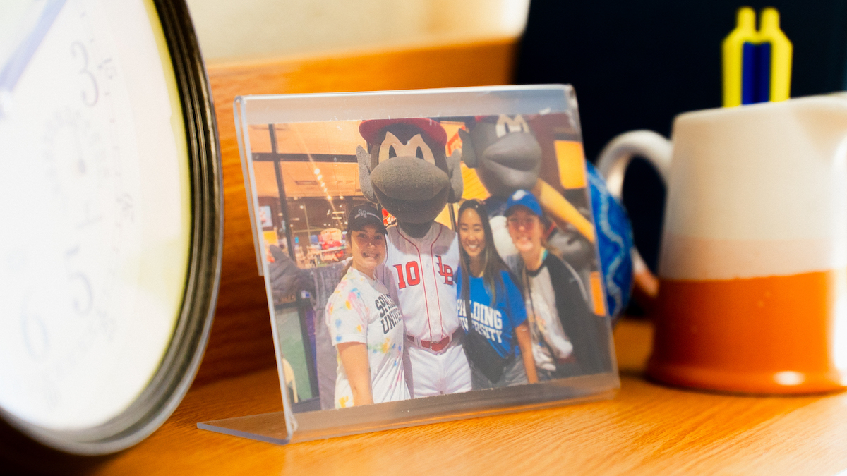 Photo sitting on a dorm room desk of three Spalding students at a Louisville Bats game