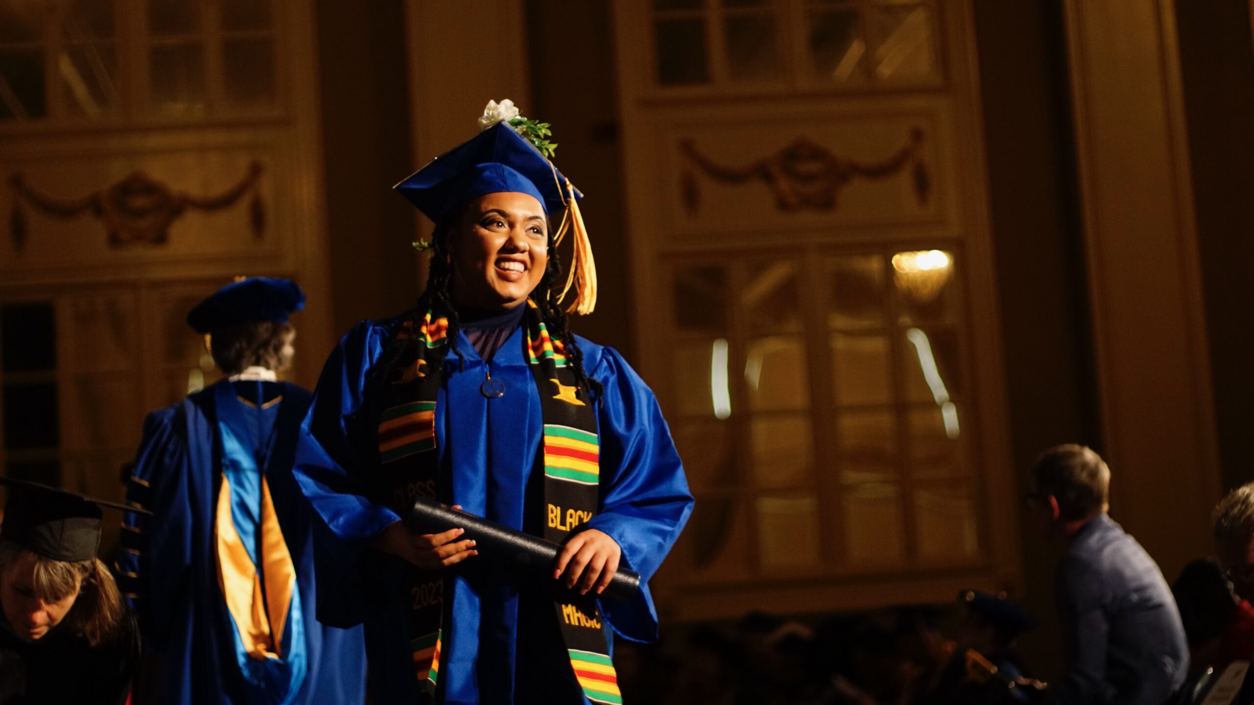 Spalding bachelor's graduate in cap and gown with degree tube