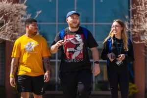 three students walking and talking outside on campus