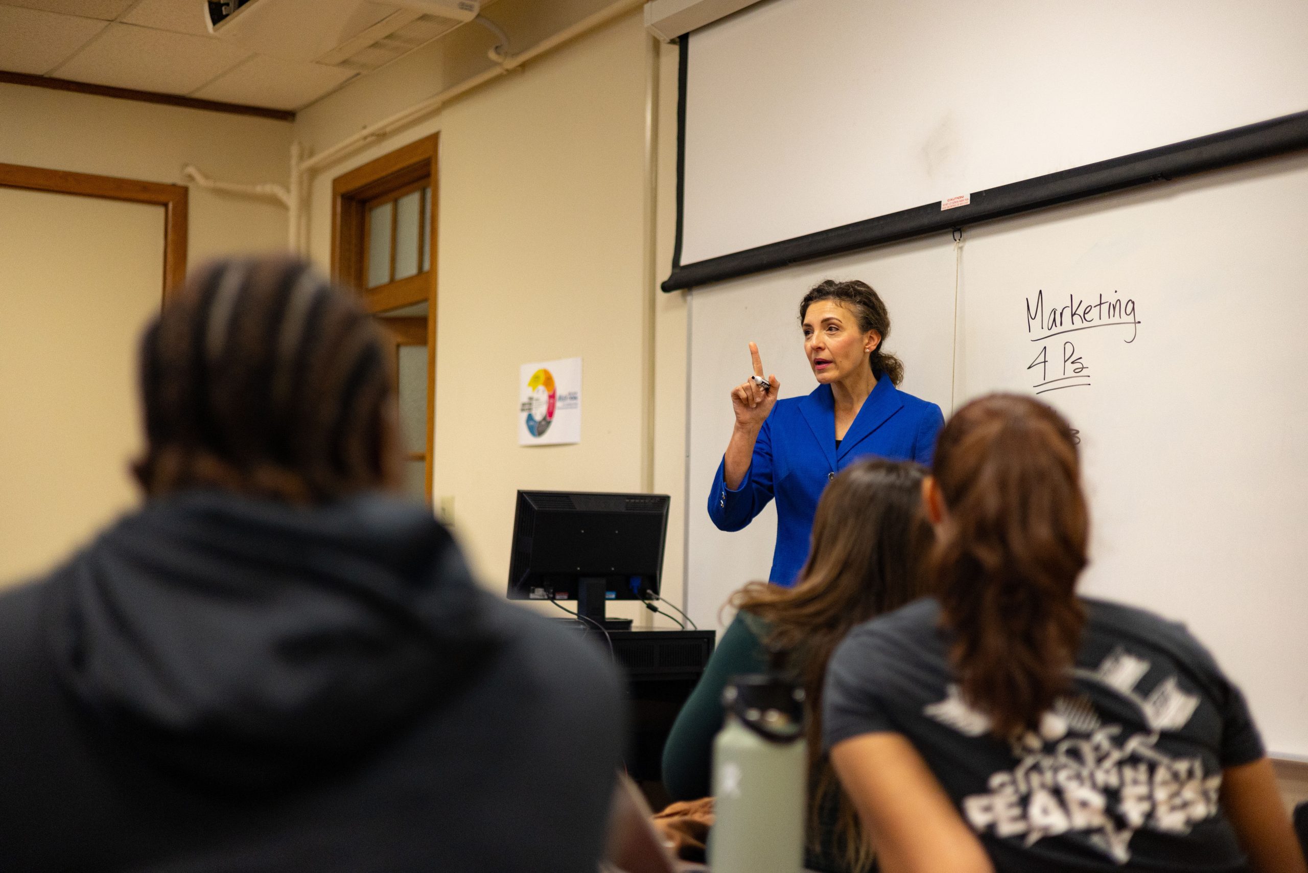 A female business professor stands in front of a classroom during a business class lecture